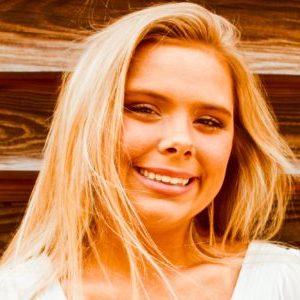 Beautiful young woman standing in front of barn; smiling head shot.